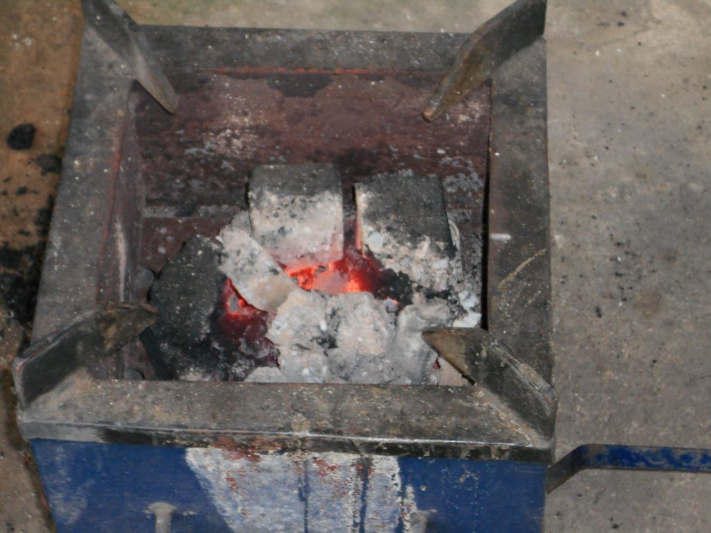 un brasereau contenant des morceaux de charbon écologiques chauds, prêts pour la cuisson des repas