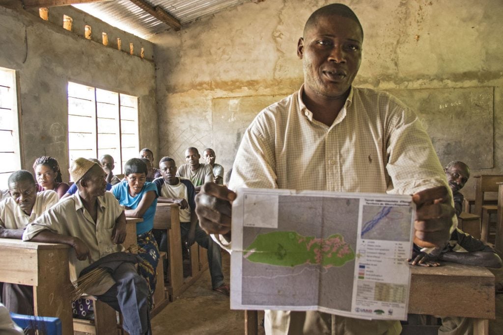 A man in Ilanga, DRC showcases a map his community created of their land and resources. The production of maps like these is an important part of the community forest concession process, as it requires community members to work together to determine boundaries and identify priority places to protect. (Photo by Molly Bergen/WCS, WWF, WRI)